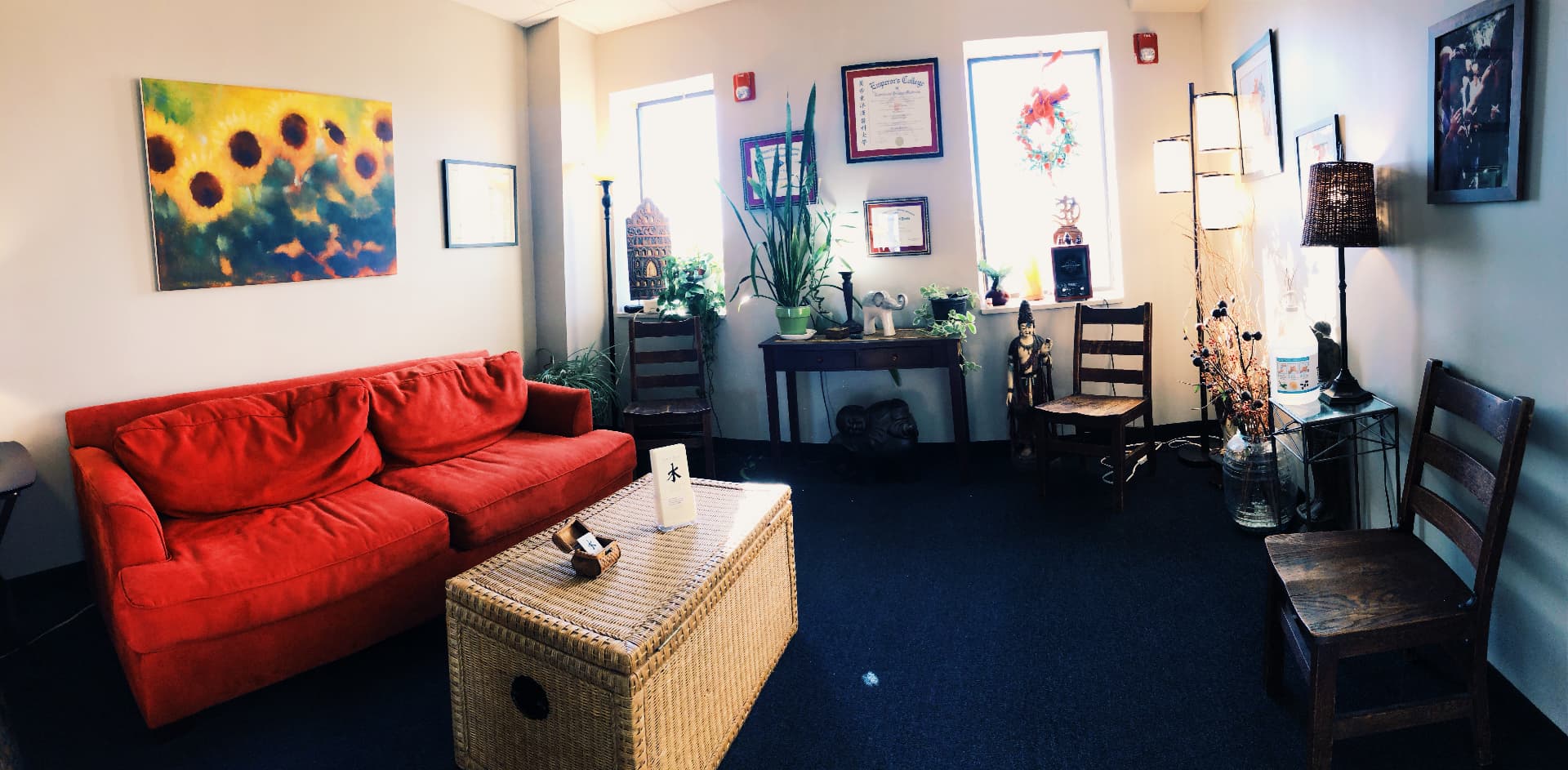 Waiting room with red couch and sunflower painting, wider view