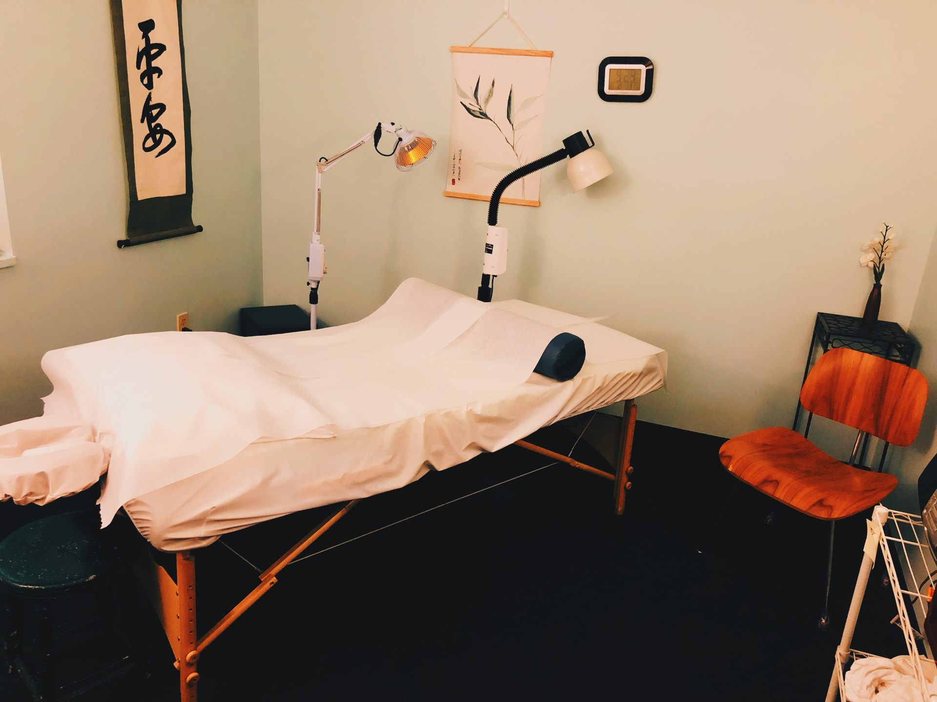 Treatment room with heat lamps, calligraphy scroll, and a wooden chair